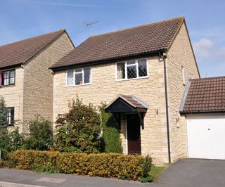 A small detached house with stone walls and a brown tiled roof