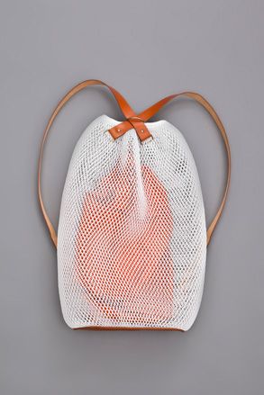 White net bag with brown leather handles, photographed against grey background