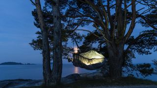 Sleeping bag suspended between trees at night