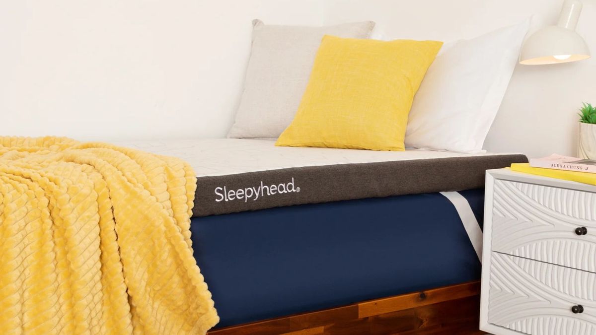 The Sleepyhead Cooling Copper Topper on top of a bed in a bright, clean dorm room.