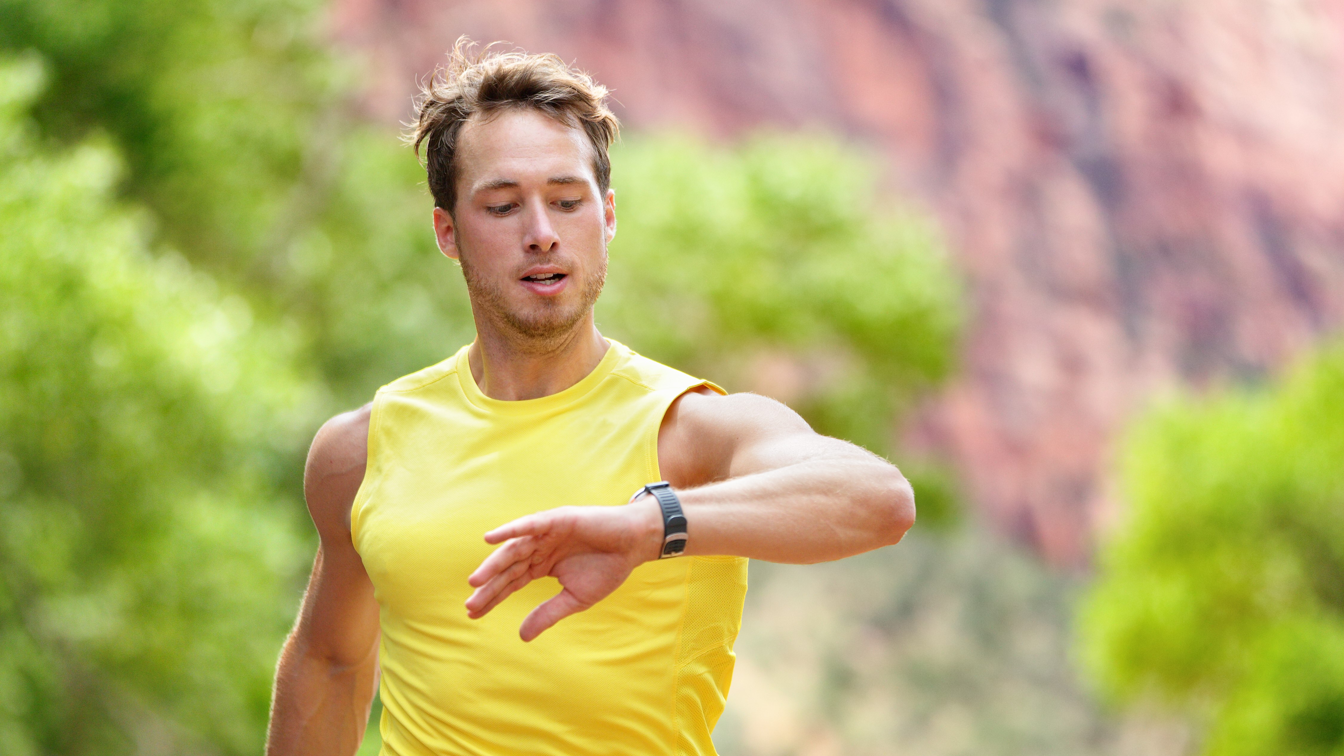 Man running off-road, checking his running watch