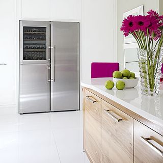 kitchen area with fridge freezer and white wall with flower on glass jar