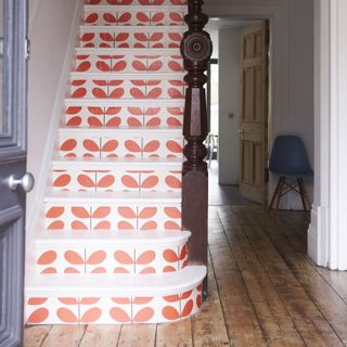 Hallway with orange Orla Kiely wallpaper on the stairs.