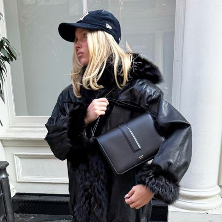 Elsa Hosk wearing light-wash jeans and heels with a leather jacket and baseball cap