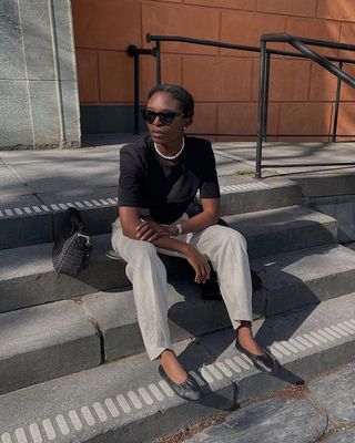 12 Scandi Outfit Ideas: Chrystelle wears linen trousers with a black T-shirt and ballet flats.