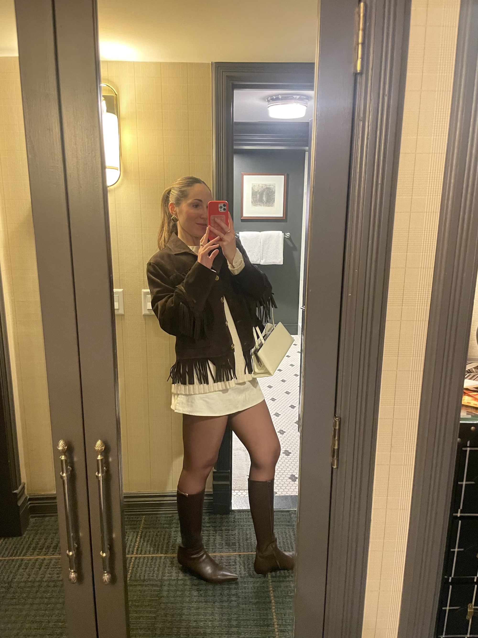 Anna LaPlaca wearing a brown suede fringe jacket with brown boots and a cream sweater in Aspen.