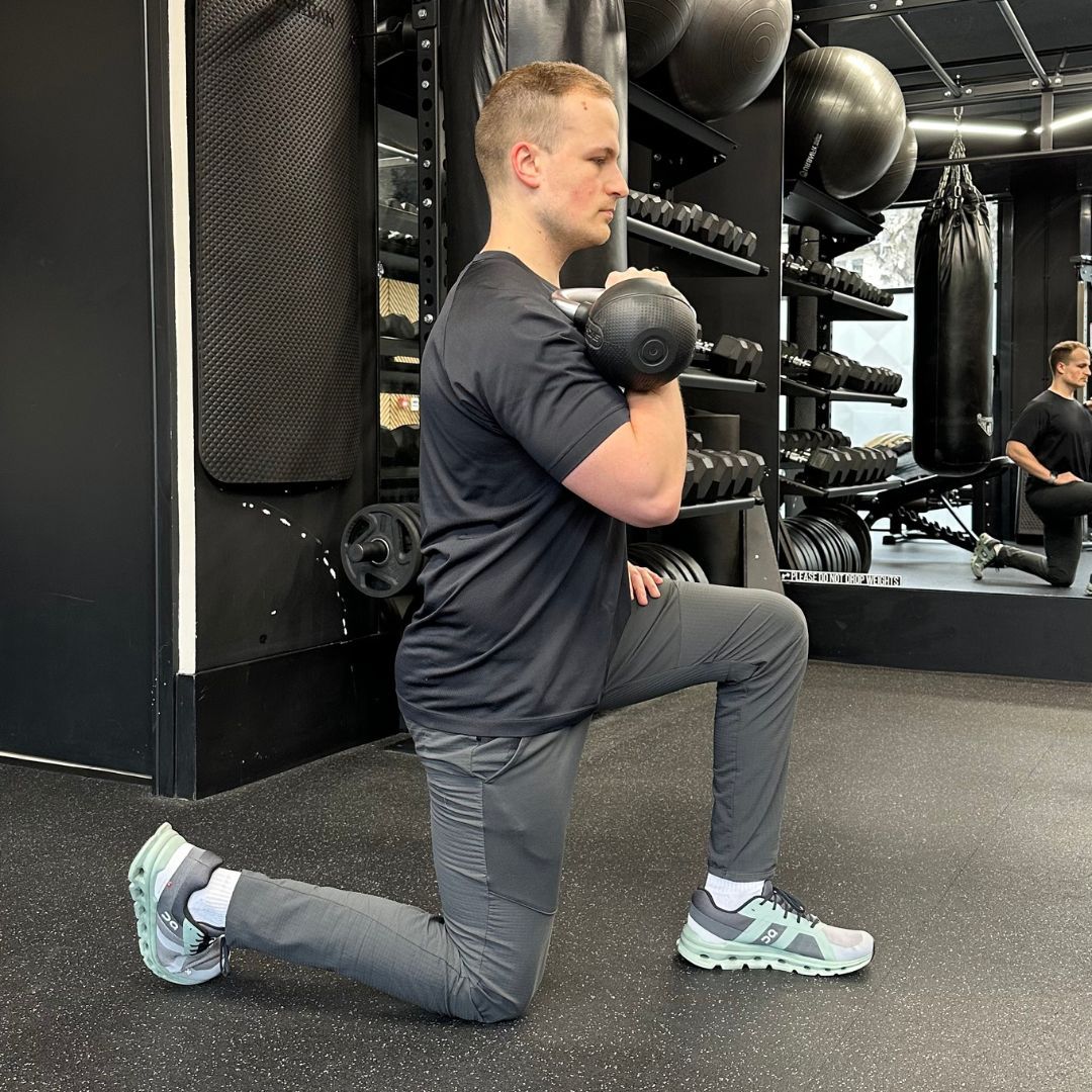 Personal trainer Ollie Thompson demonstrating a half-kneeling kettlebell press