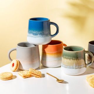 Sass & Belle Mojave Glaze Mug in blue, orange , grey and green with biscuits