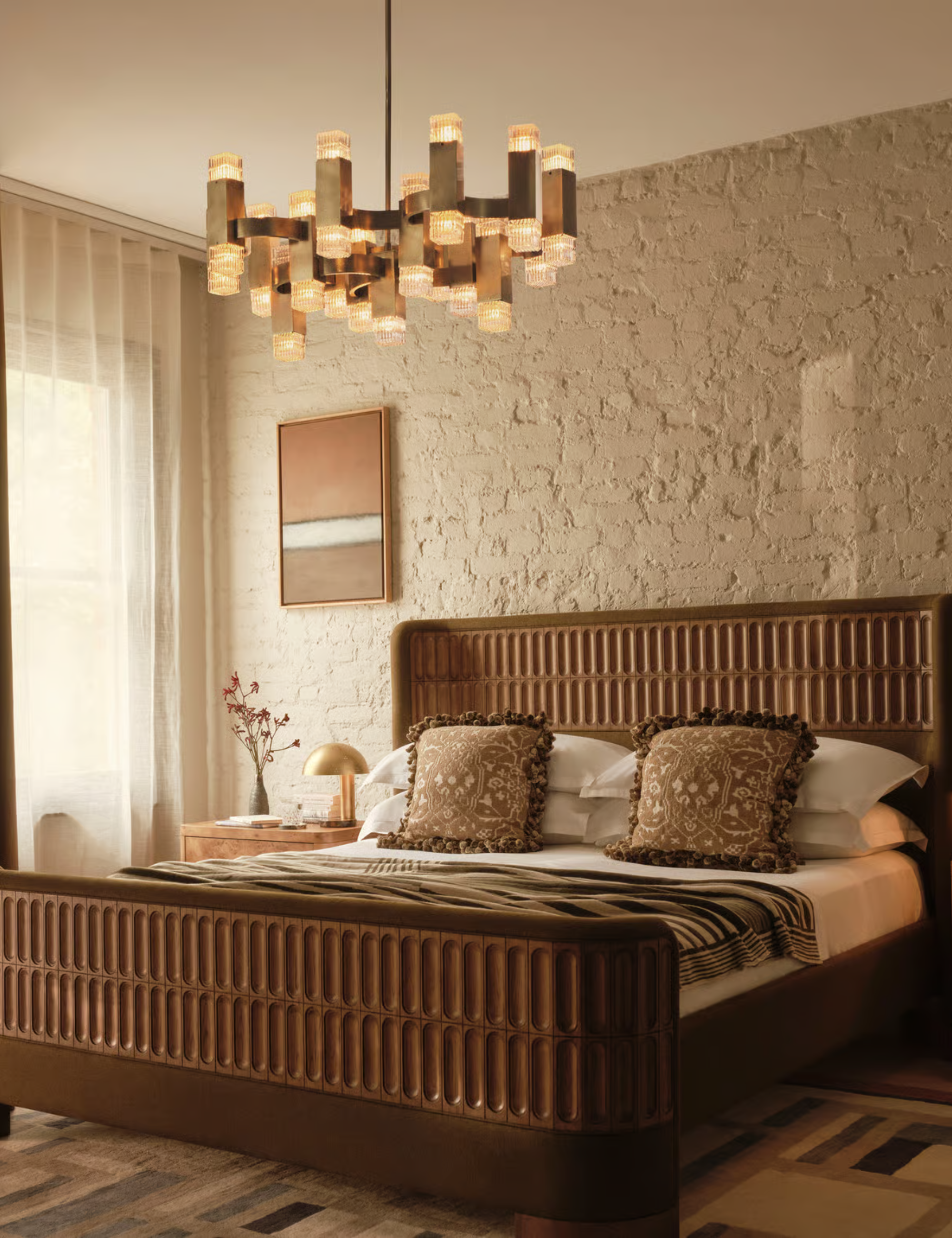 Soho Home wooden bed pictured in a neutral bedroom with brick walls and a modern chandelier