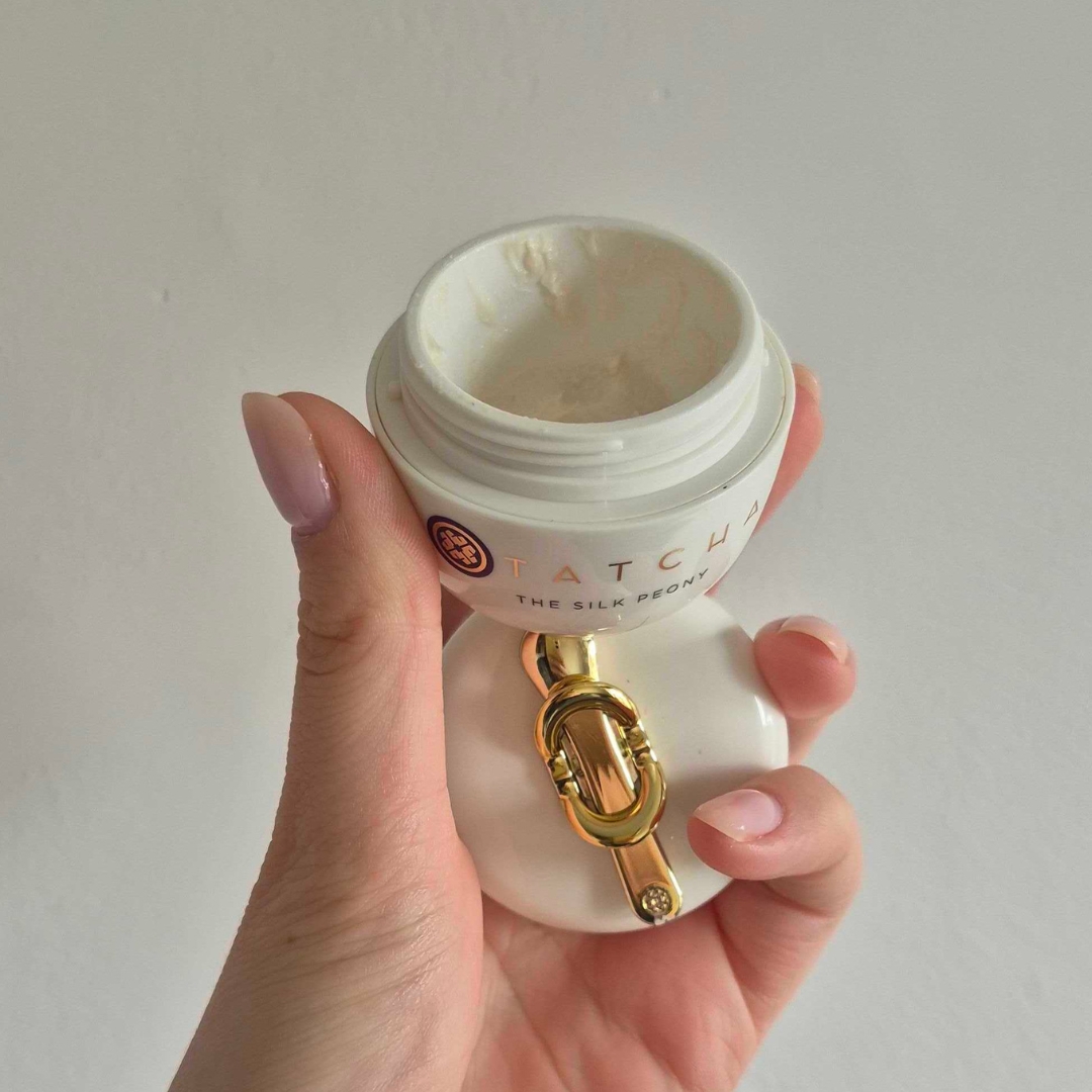 Hand holding empty tub of the Tatcha The Silk Peony Eye Cream