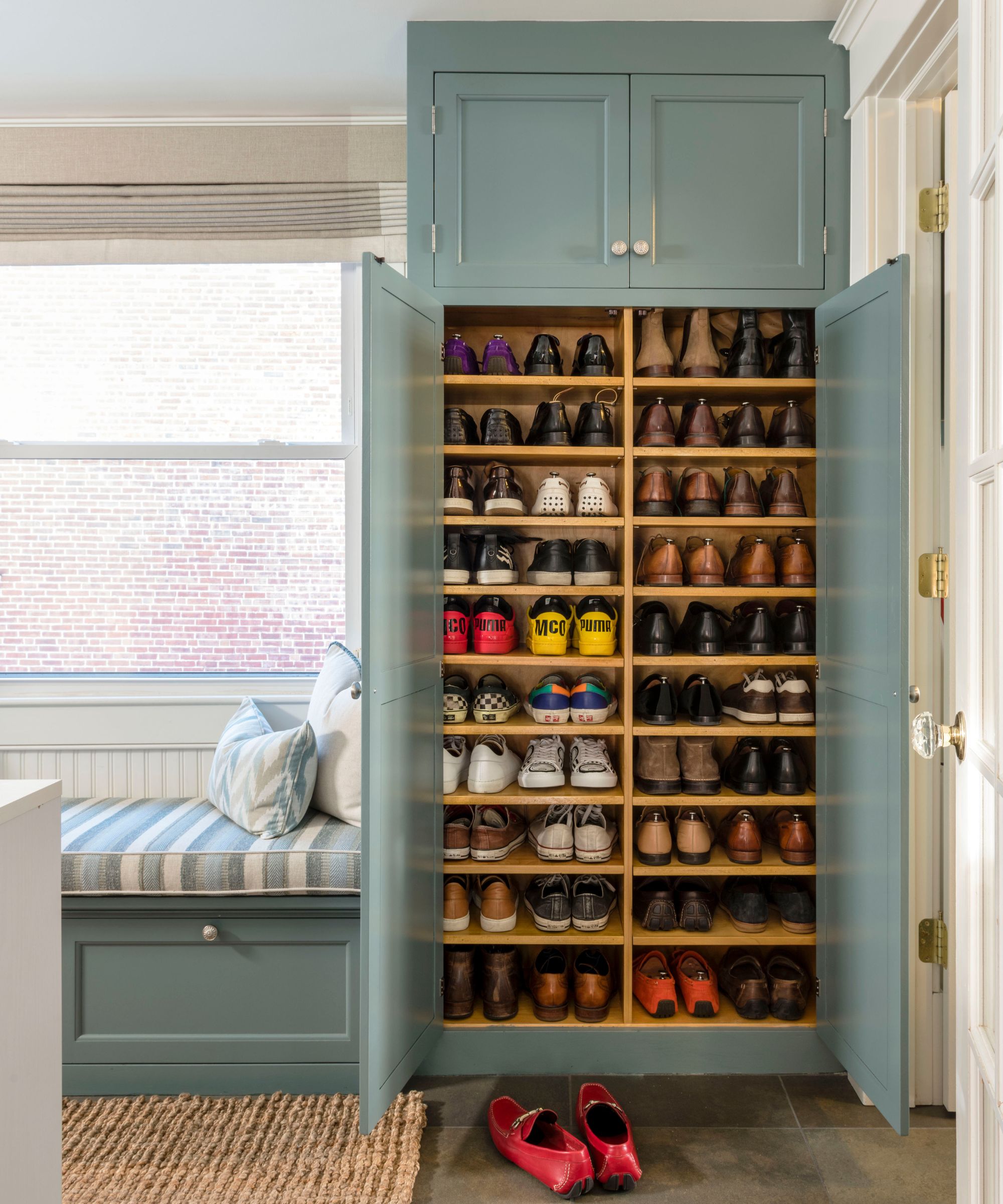 Entryway with a pale blue painted cupboard for shoes and a built-in bench, with a rattan rug on the floor