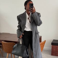 Marilyn NK wearing a grey wool coat, white shirt and black trousers.