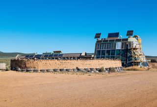 Earthship community in Taos showing colourful off grid homes nestled into the desert earth