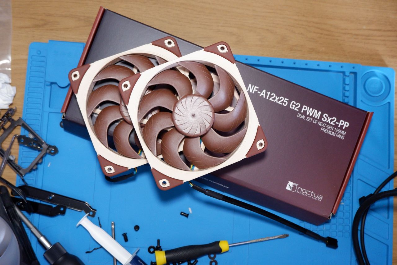 A set of Noctua NF-A12x25 G2 PC fans on a desk with packaging.