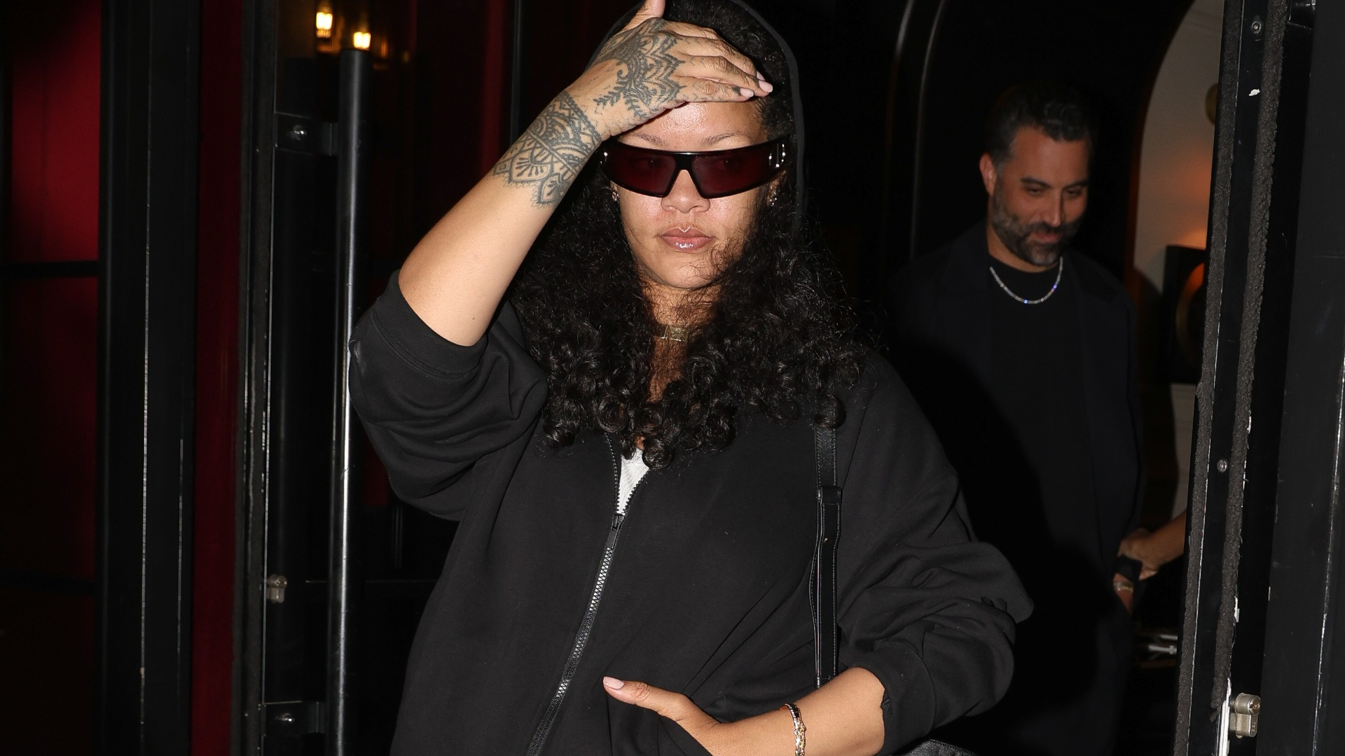 Rihanna styled a black hoodie and Dior bag with hybrid skirt and jeans bottoms