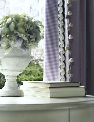 Small check print lilac curtain details with frill and tasselled trimmings.