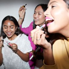 Best pink lipsticks - young women in front of mirror applying lipstick