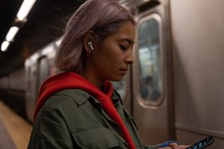 Woman wears AirPods Pro while waiting in train station