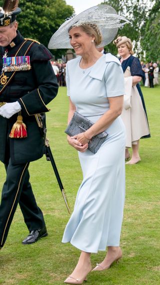 Duchess Sophie wears a blue dress and hat and walks across the grass during the Sovereign's Garden Party held at the Palace of Holyroodhouse on July 2, 2024