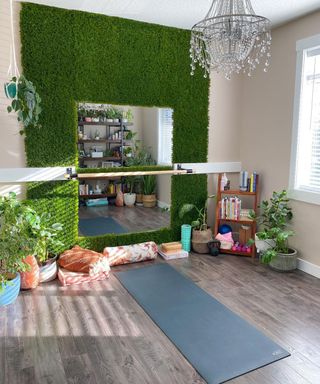 A home gym with faux living wall surrounding mirror