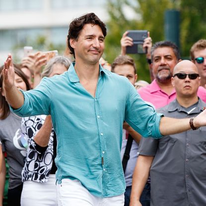 Justin Trudeau walks with arms open wide as if going in for a hug.