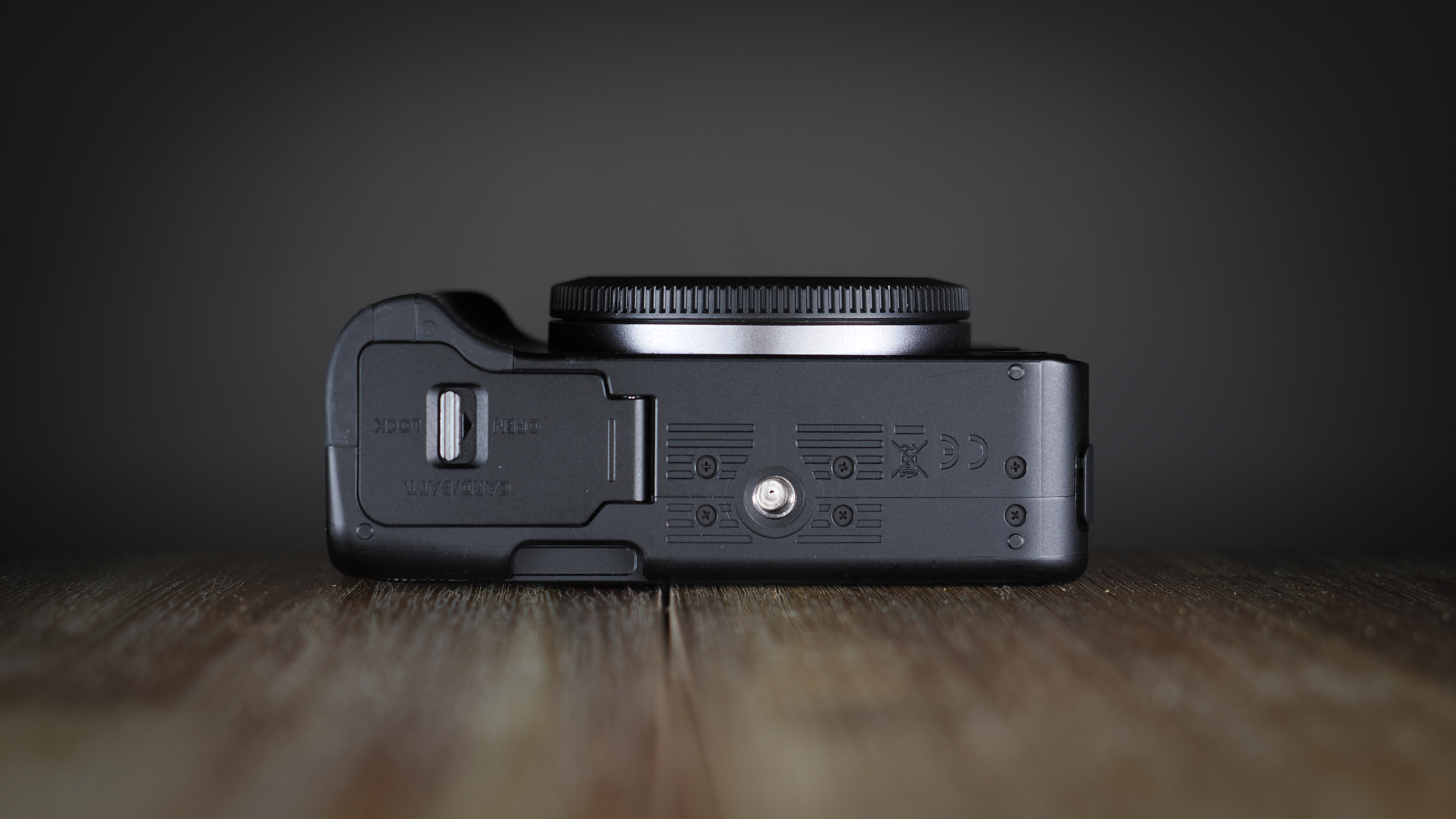 Canon EOS R50 V on a wooden surface, against a dark background