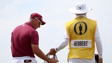 Lucas Herbert wipes his hands on a towel next to his caddie