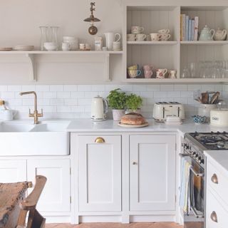White shaker kitchen with brass cup handles and a white belfast sink.