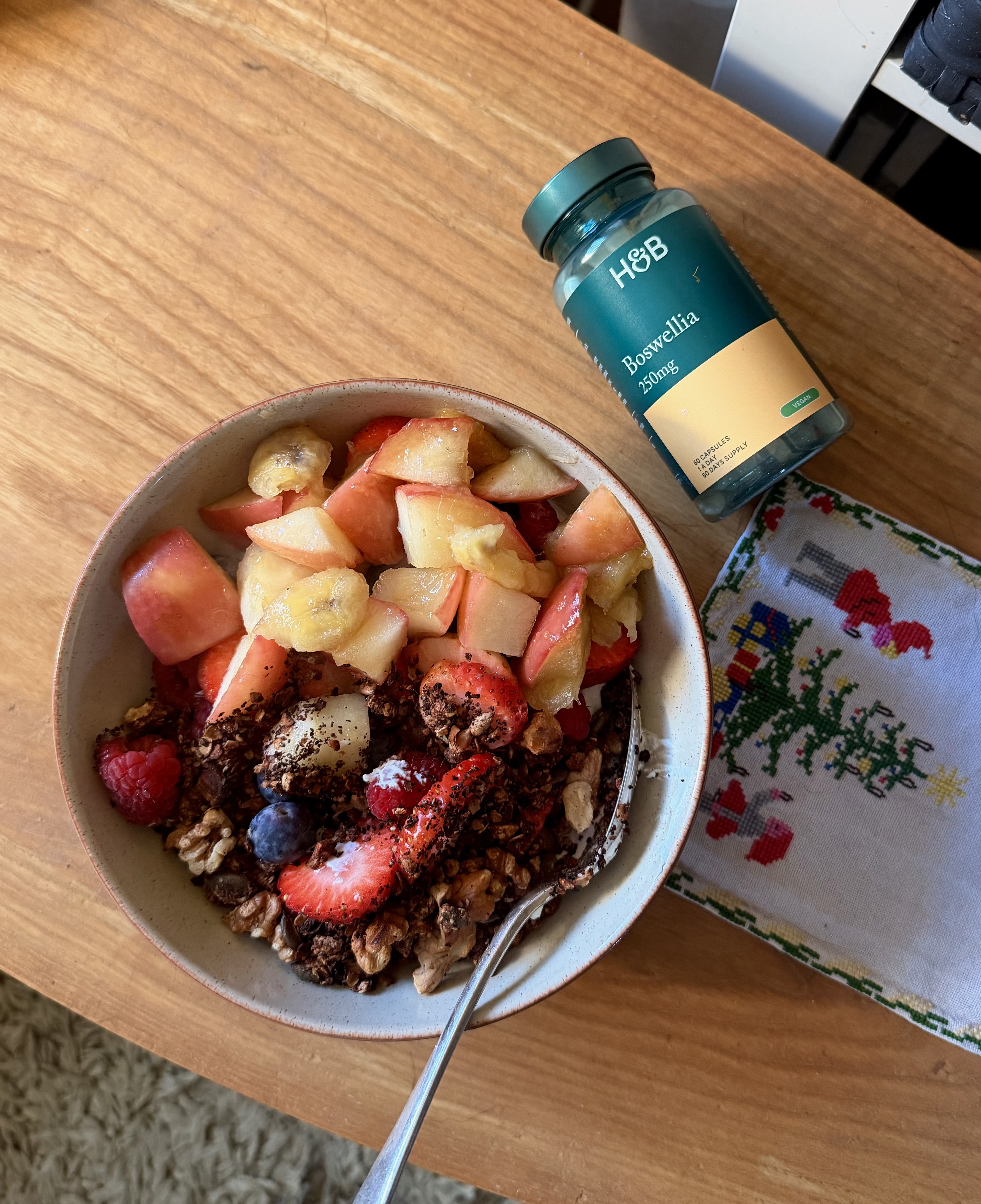A yoghurt bowl full of fruit and granola alongside a bottle of Boswellia Serrata supplements
