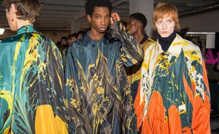 3 male models in a crowded room wearing colourful coats