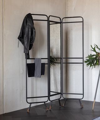 A mirrored room divider with clothes hung on top by Cuckooland and Dutchbone