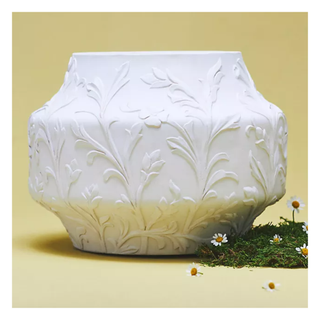 A white planter with embossed floral design