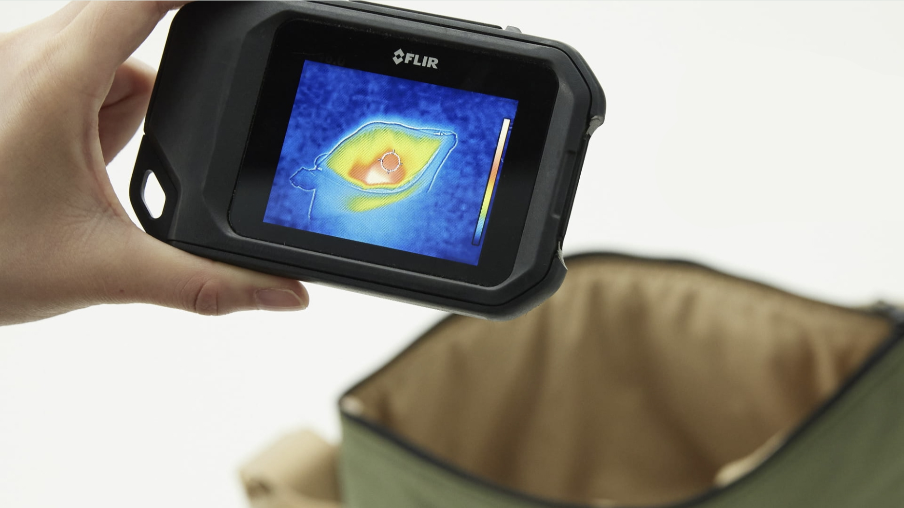 A handy holding an infrared thermometer in front a heatable bag