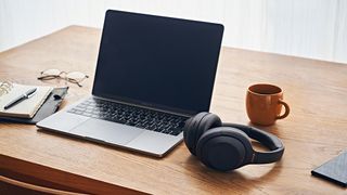 Sony WH-1000XM4 headphones in black on a desk next to a laptop