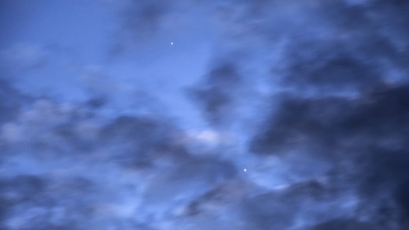 a photo of the sky at dawn with Mercury and Venus visible behind dark clouds