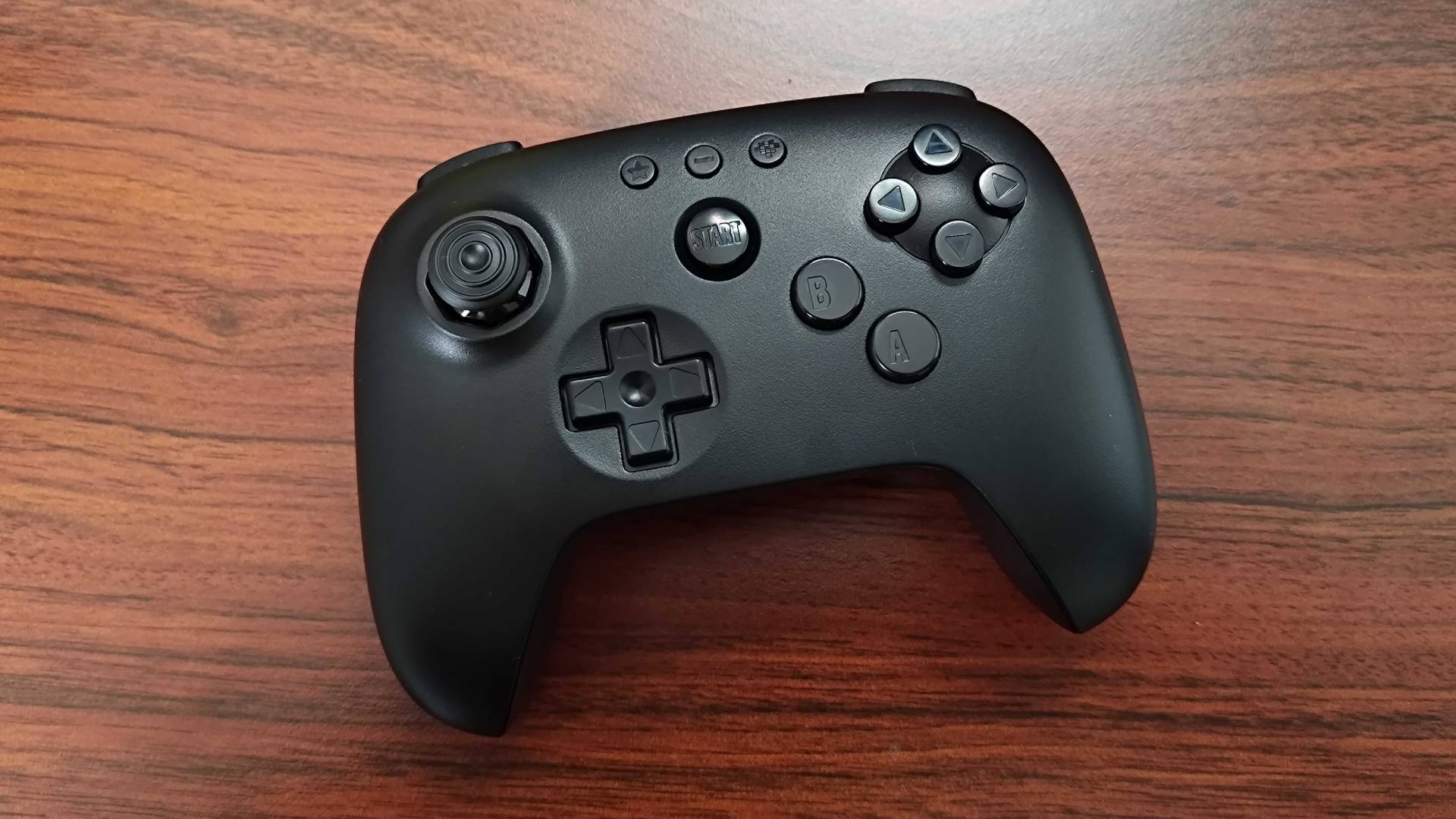 8Bitdo N64 Bluetooth controller sitting on woodgrain surface.