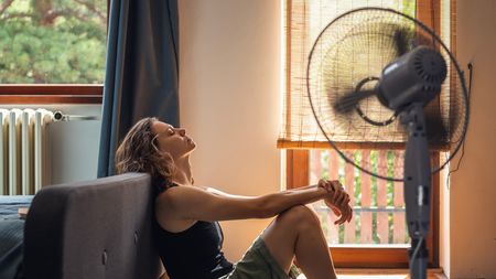 A woman sat in front of a cooling fan in a heatwave