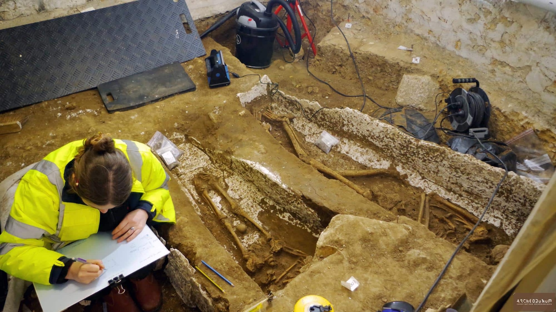 A woman writes on a piece of paper in the excavation site