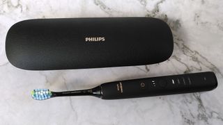 Philips Sonicare DiamondClean 9000 electric toothbrush beside charging case