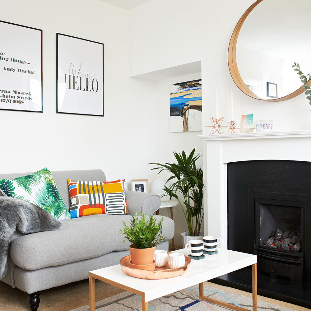 white living room with coffee table sofa with color patterned pillows and fire place