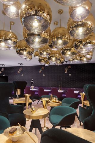 There is a beautiful dining room with a goden table and a goden dinner set as part of the Tom Dixon Sandwich
