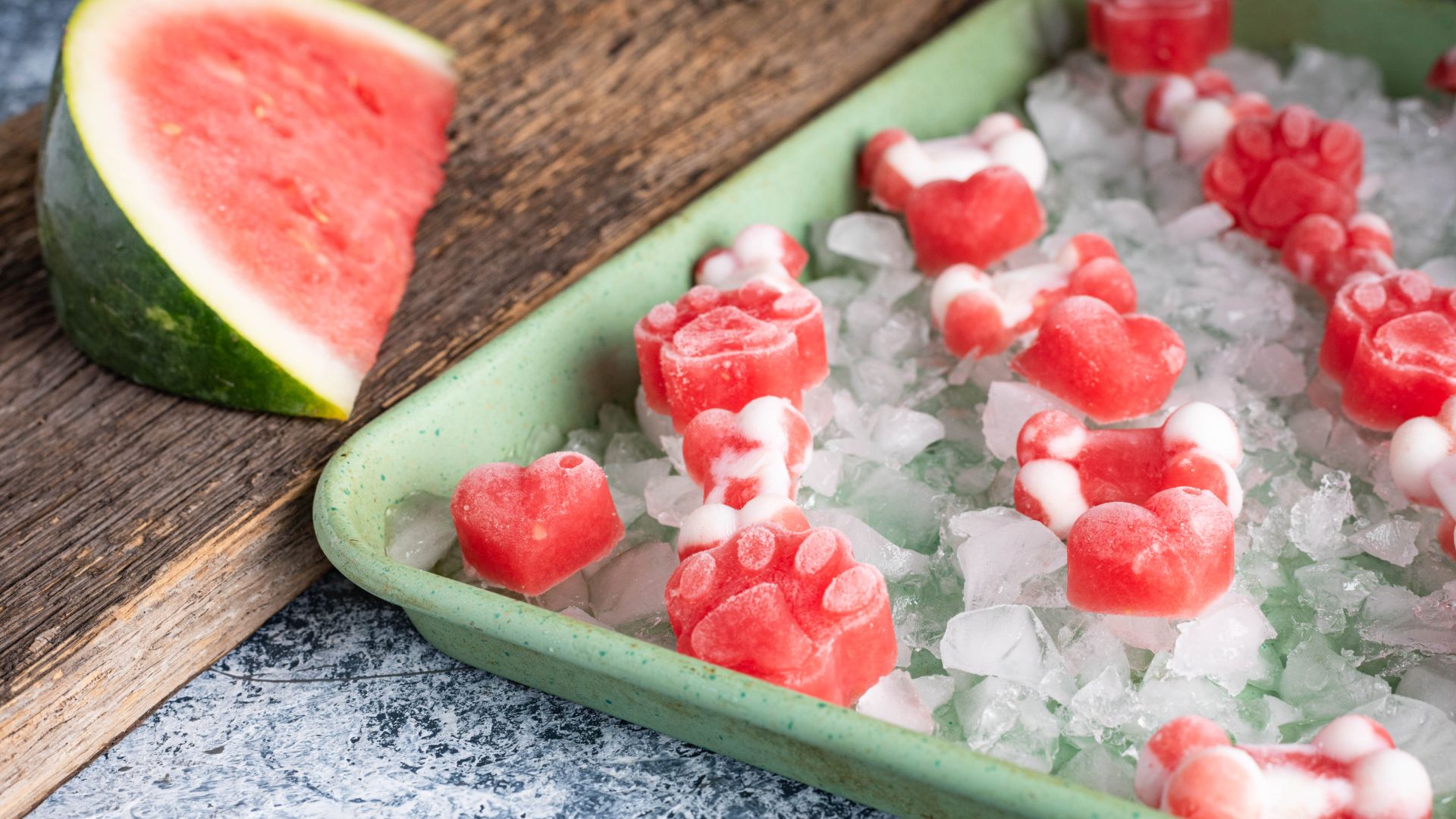 tray of ice with frozen paw-shaped watermelon ice cubes