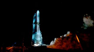 a large white rocket fires its seven engines on the launch pad as a test