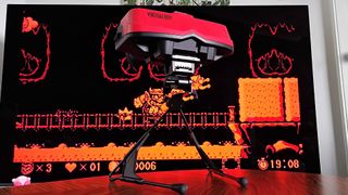 Virtual Boy for Switch 2 sitting on coffee table with TV in backdrop displaying Wario Land gameplay.