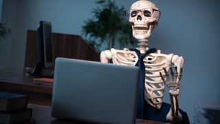 Das Skelett eines Büroarbeiters wartet darauf, dass sein Laptop startet