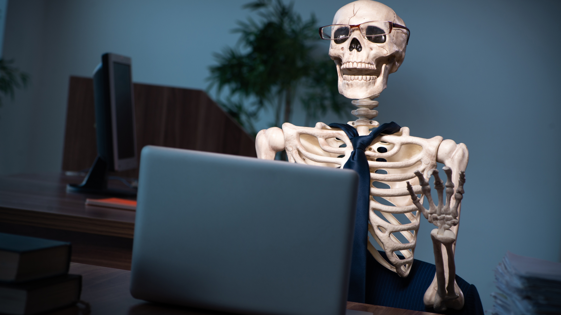 Esqueleto de un oficinista esperando a que arranque su portátil