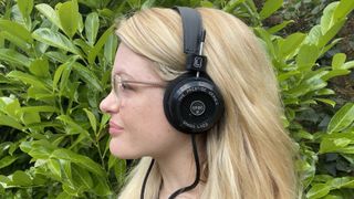 Becca Caddy wearing the Grado SR80x headphones against a green background.