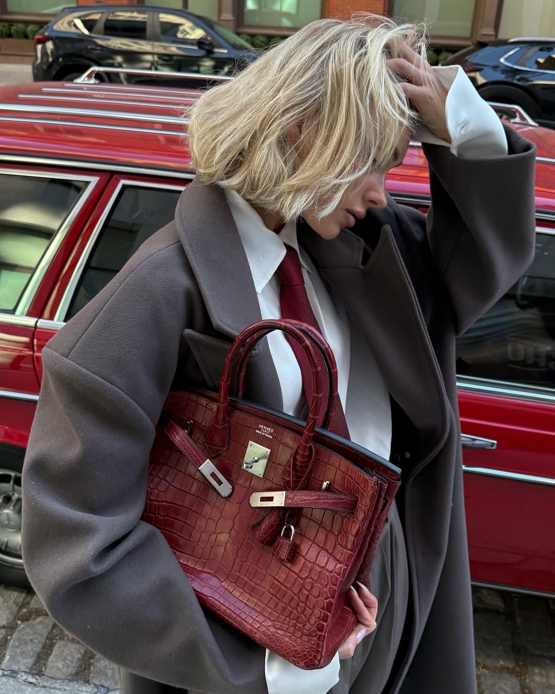 Elsa Hosk with a blonde bob haircut, holding an Hermes Birkin bag