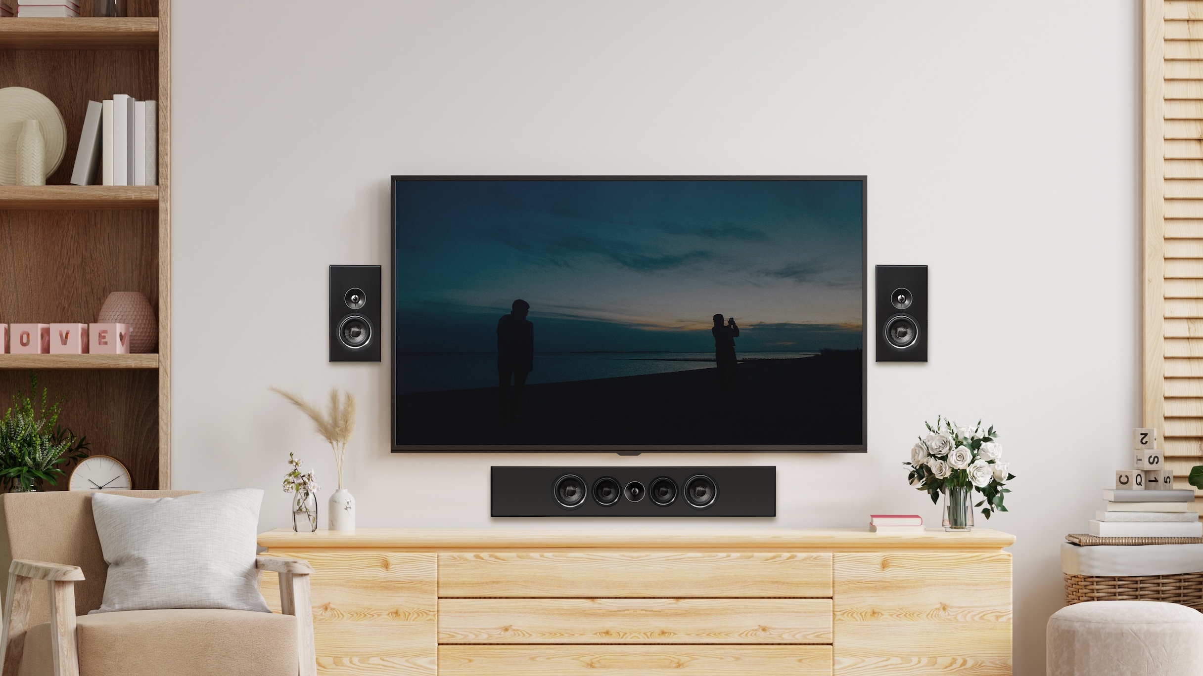 A pair of PSB PWM Sat speakers wall-mounted either side of a wall-mounted TV in a light, airy lounge.