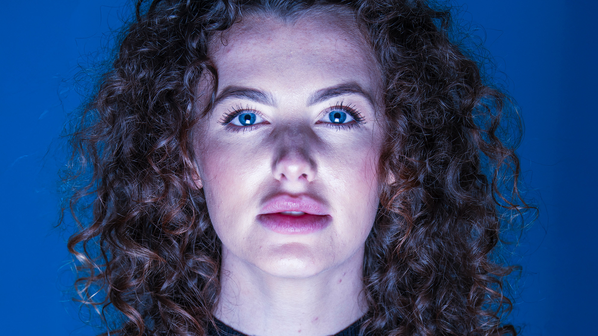 Close-up studio portrait of model by James Paterson on a blue background